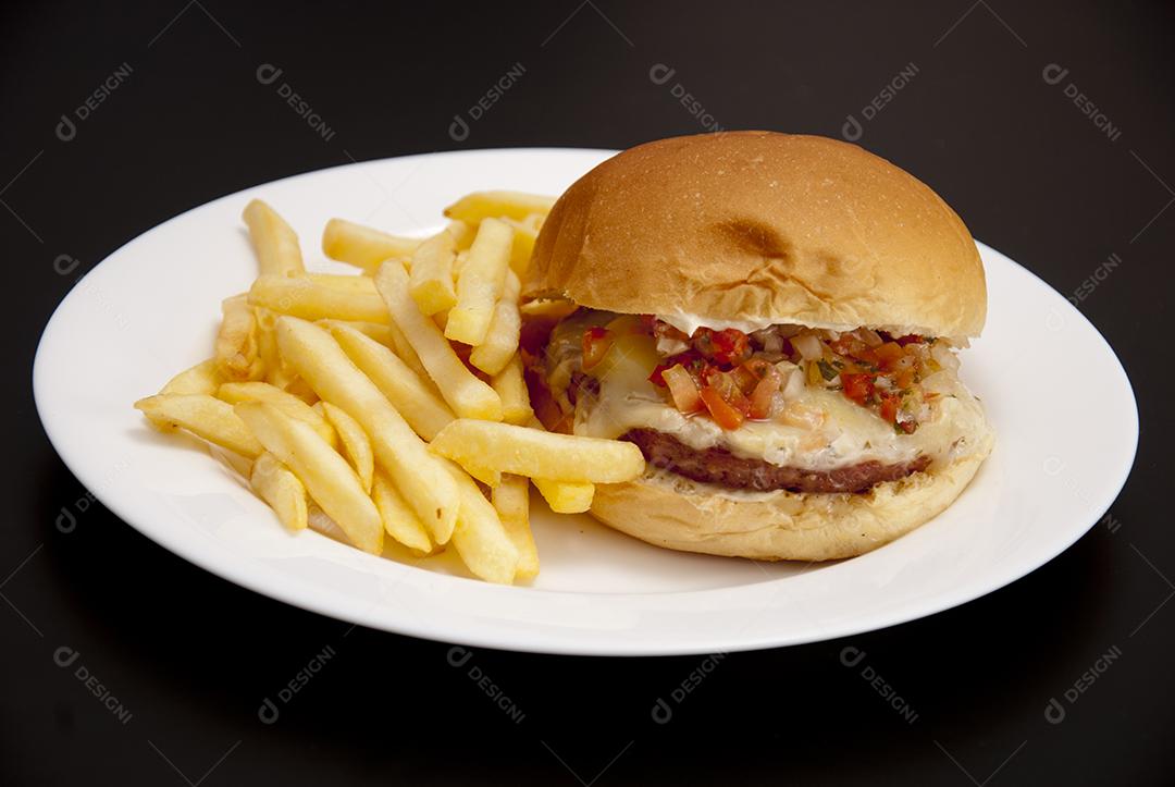 Hambúrguer com queijo derretido, maionese, alface batata frita prato branco