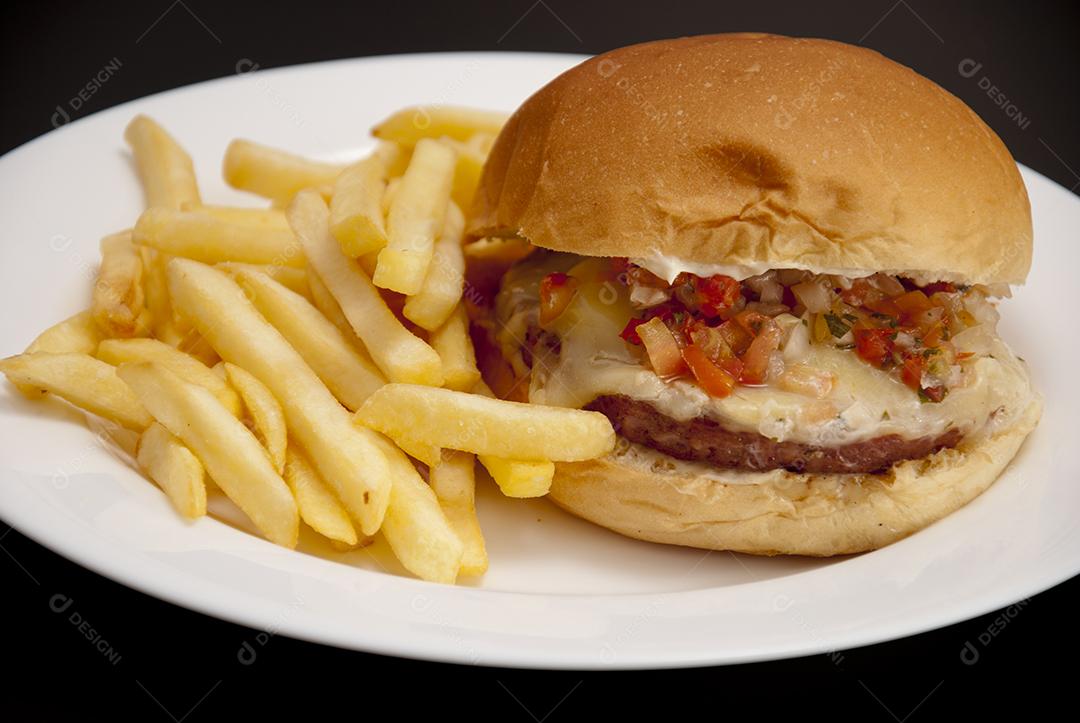 Hambúrguer com queijo derretido, maionese, alface batata frita prato branco