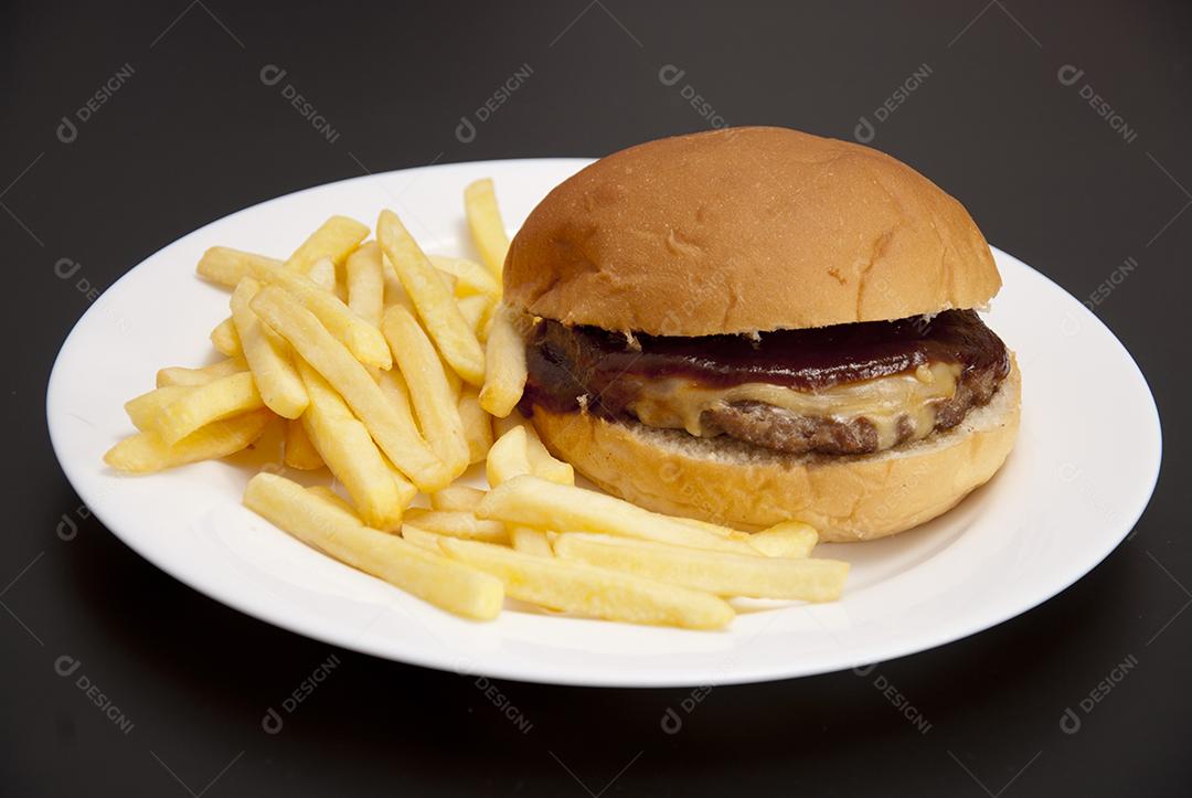 Hambúrguer com queijo derretido, maionese, alface batata frita prato branco