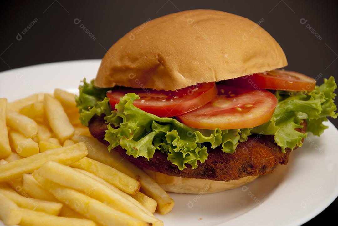 Hambúrguer com queijo derretido, maionese, alface batata frita prato branco