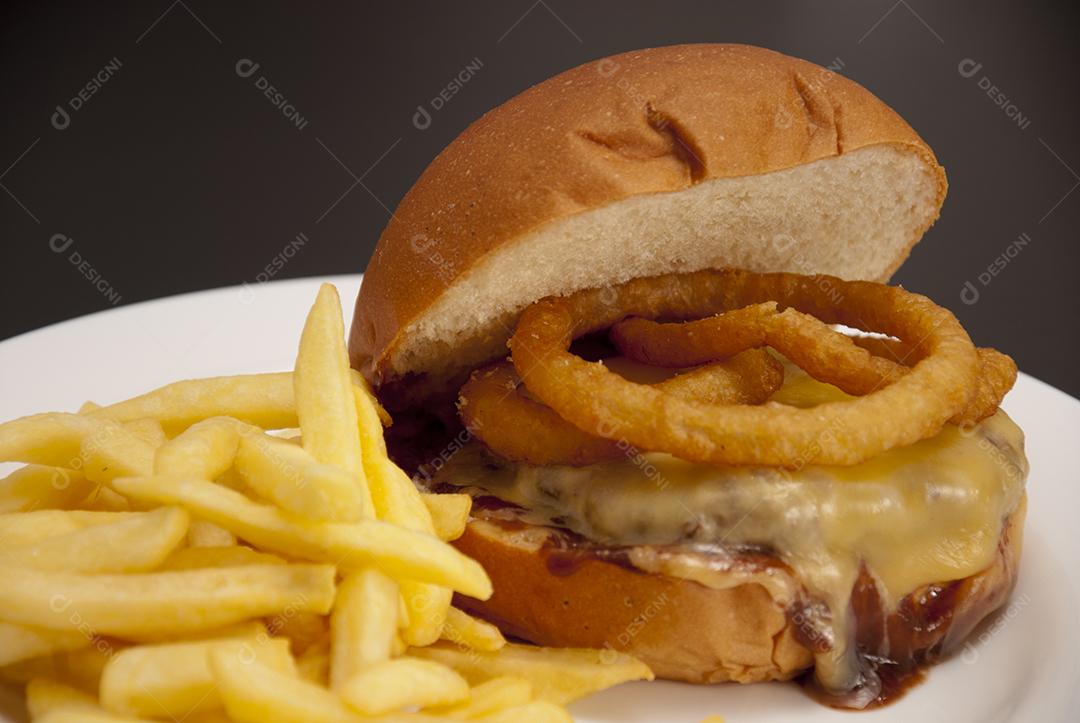 Hambúrguer com queijo derretido, maionese, alface batata frita prato branco