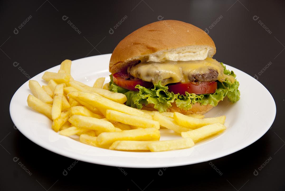Hambúrguer com queijo derretido, maionese, alface batata frita prato branco