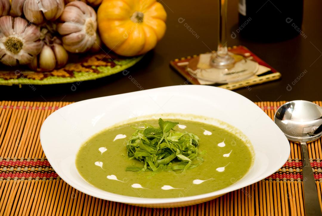 Sopa de ervilha verde servida em prato branco
