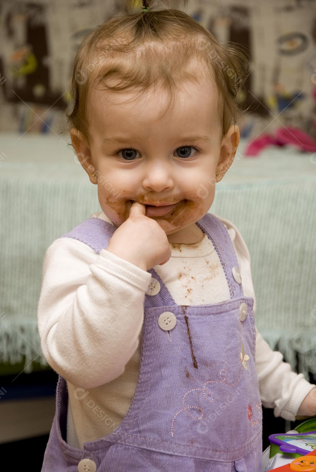 Criança com boca suja e dedo na boca