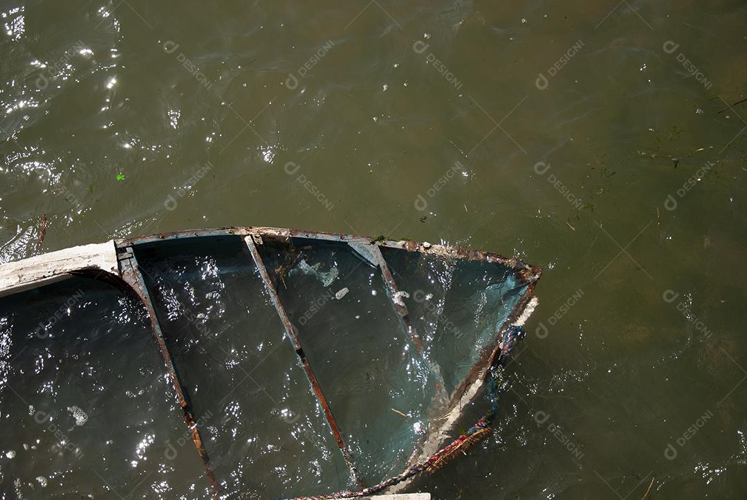 Barco naufragado em rio de aguas escuras em dia claro