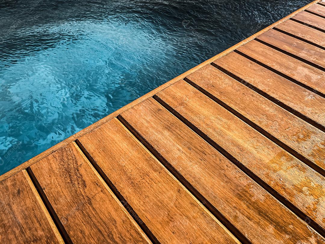 Área coberta de madeira à beira da piscina para segundo plano.