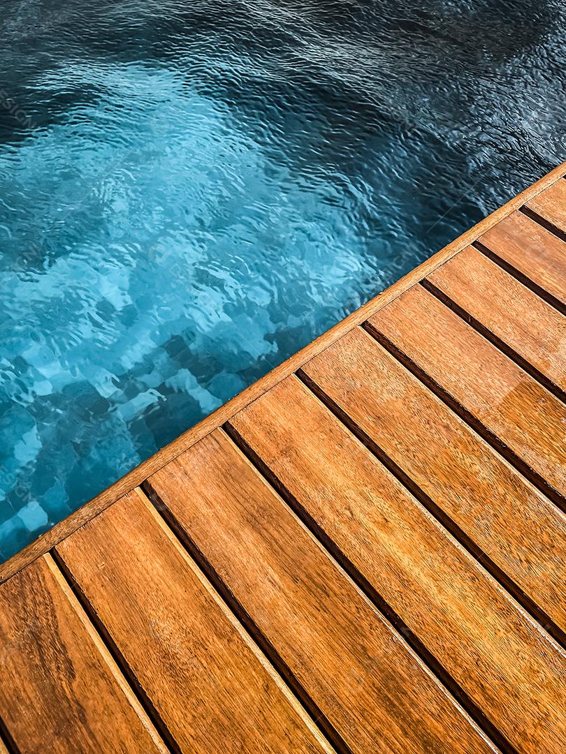 Área coberta de madeira à beira da piscina para segundo plano.