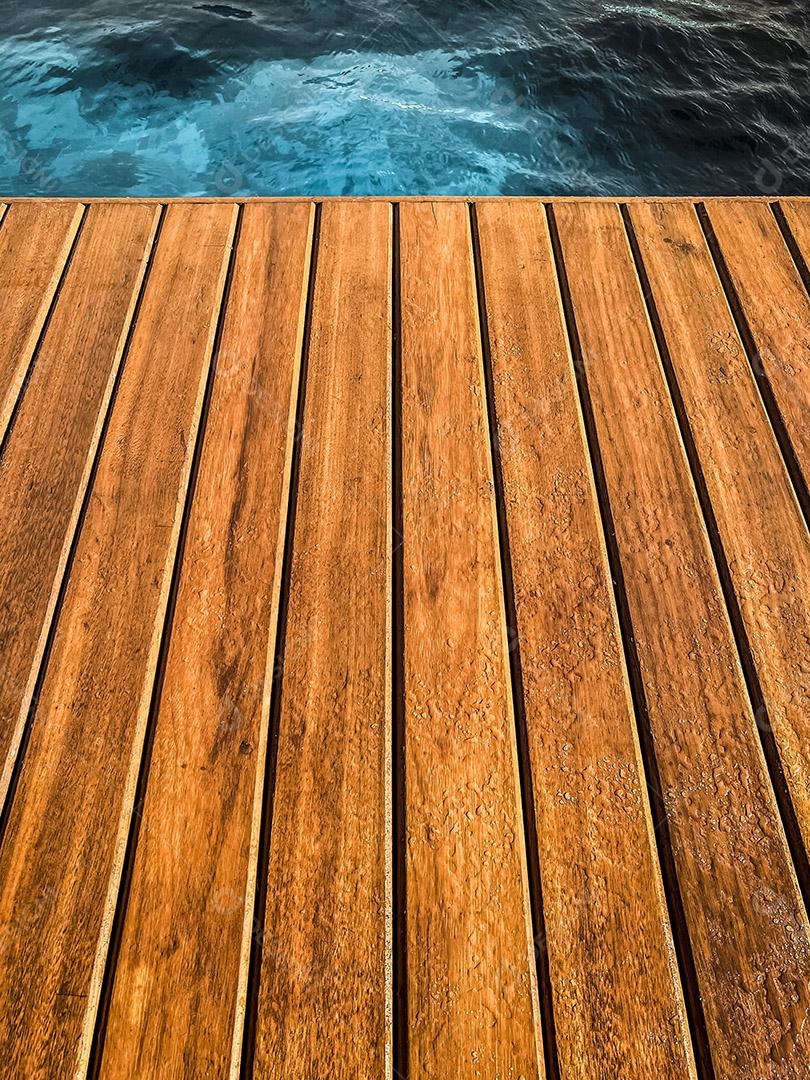 Área coberta de madeira à beira da piscina para segundo plano.