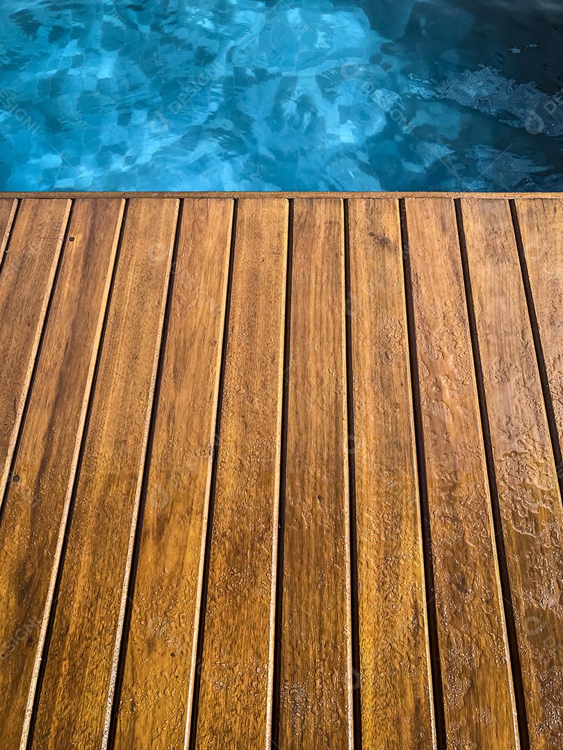 Área coberta de madeira à beira da piscina para segundo plano.