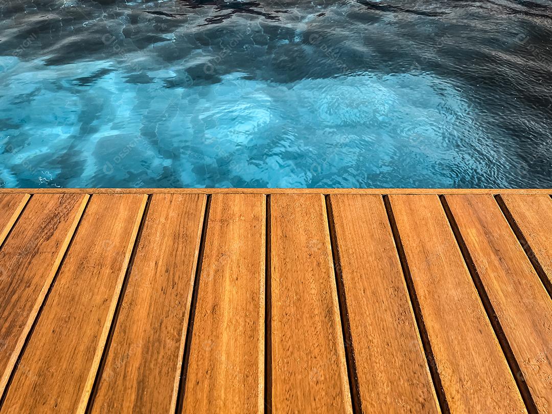 Área coberta de madeira à beira da piscina para segundo plano.