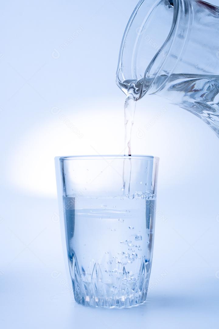 Jarra cheia de agua servindo um copo cristal