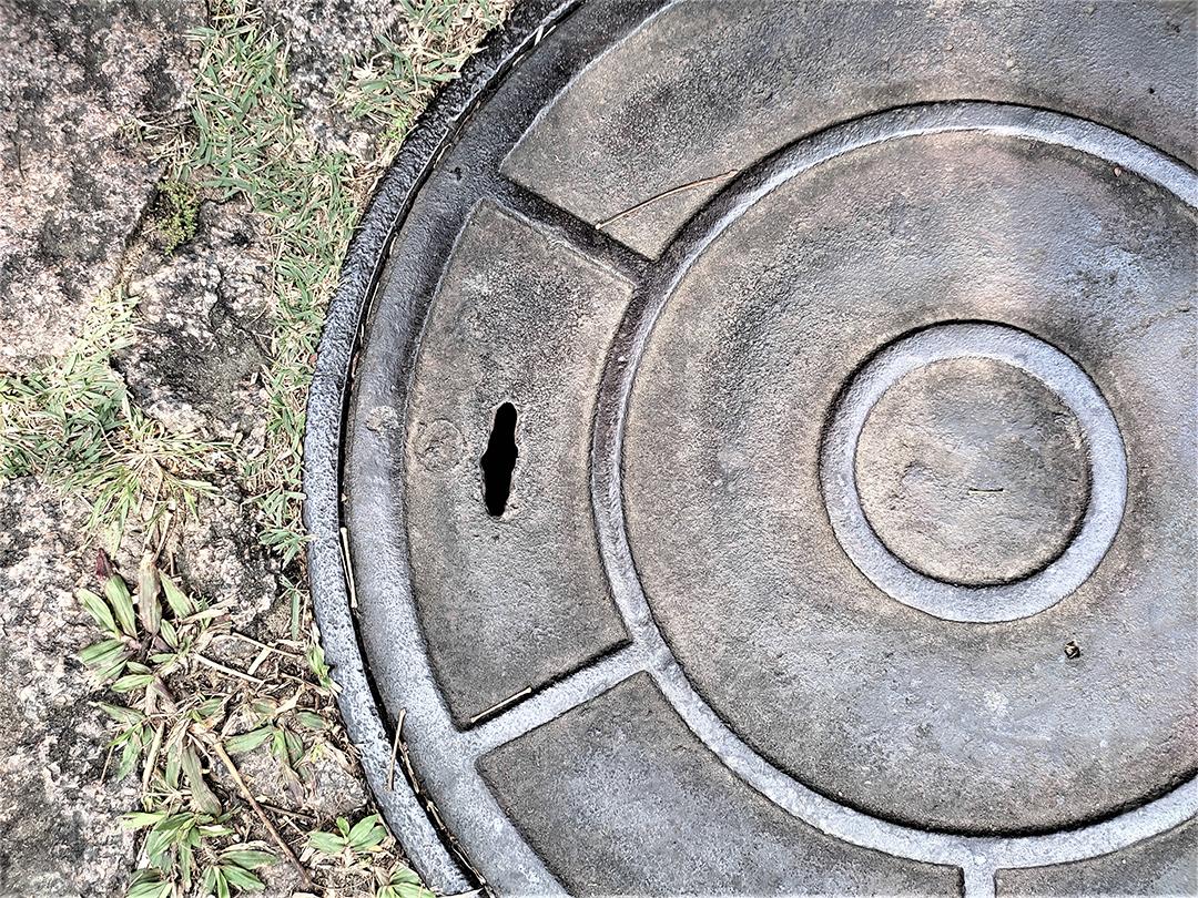 Tampa de câmara de visita redonda do esgoto na grama verde