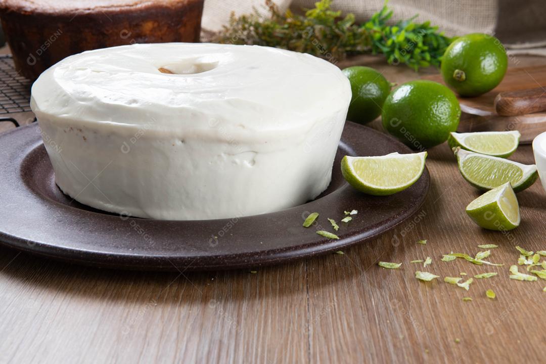 Bolo de frutas de limão úmido no prato com rodelas de limão na mesa de madeira