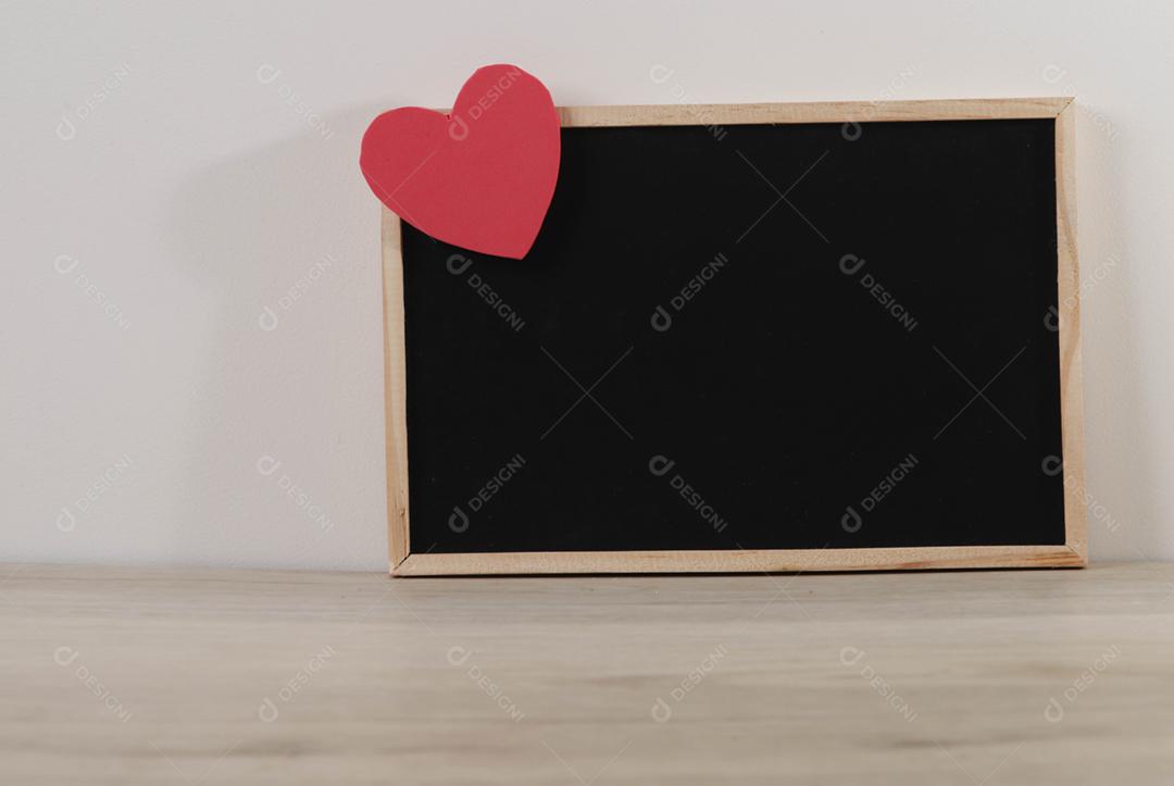 Quadro-negro e corações em fundo de madeira