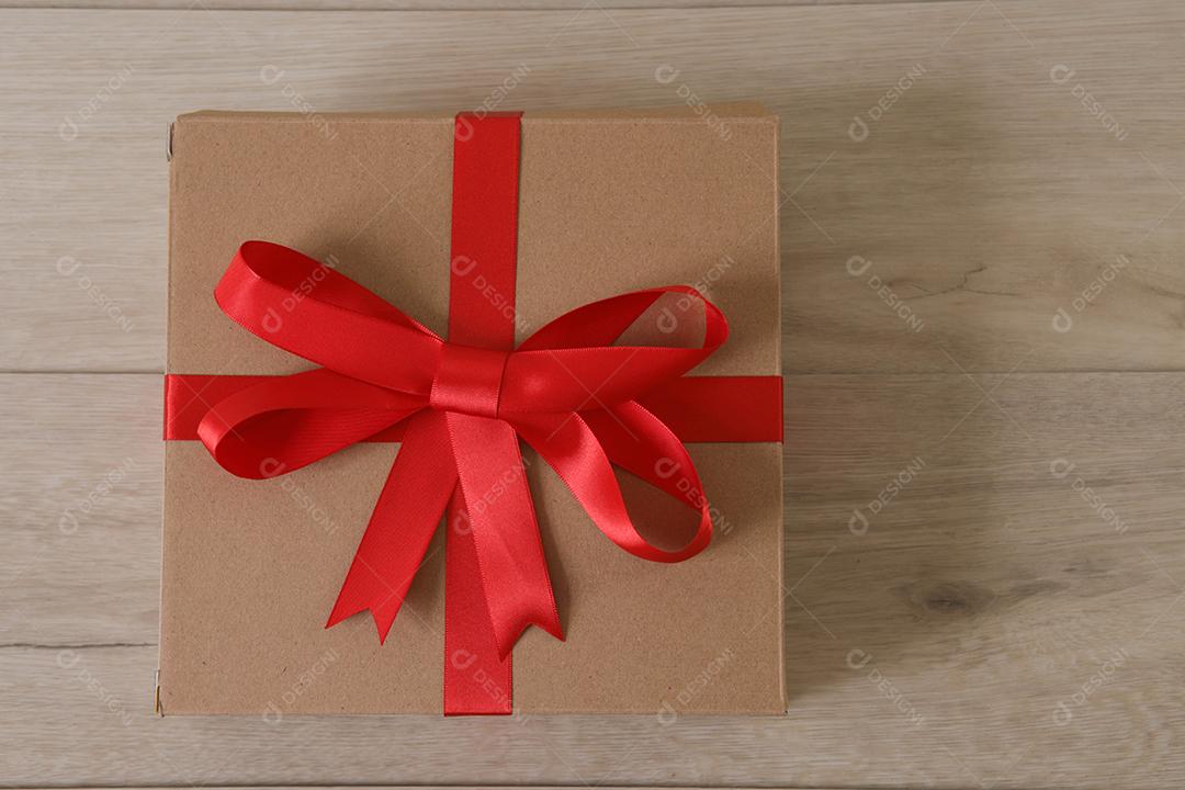 Caixa de presente marrom com fita vermelha e corações.