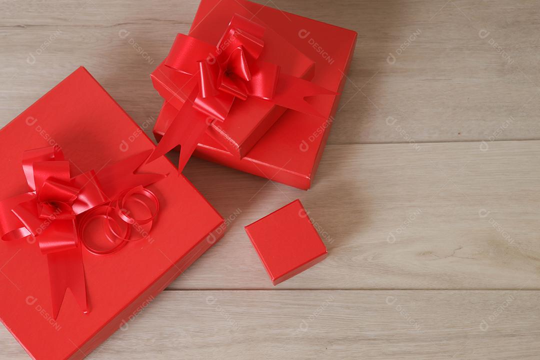 Caixas de presente vermelhas e fita vermelha em fundo de madeira