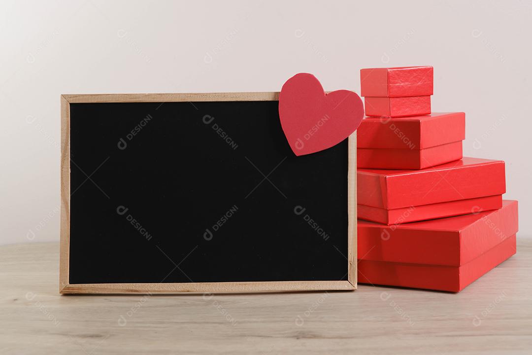 Caixas de presente vermelhas no fundo da parede com quadro-negro e coração.
