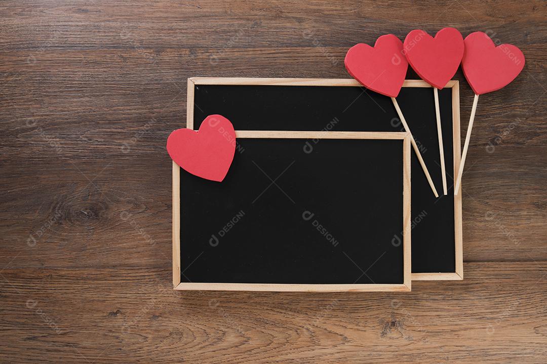 quadro-negro com sacola de compras, presente e corações em fundo de madeira