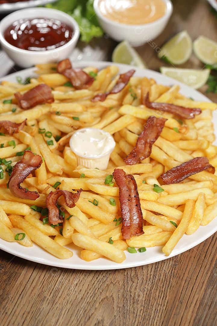 Porção de batata frita com bacon. Alface, cebolinha, tomate, ketchup e maionese.