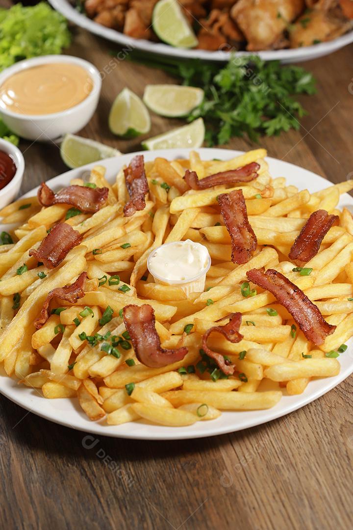 Porção de batata frita com bacon. Alface, cebolinha, tomate, ketchup e maionese.