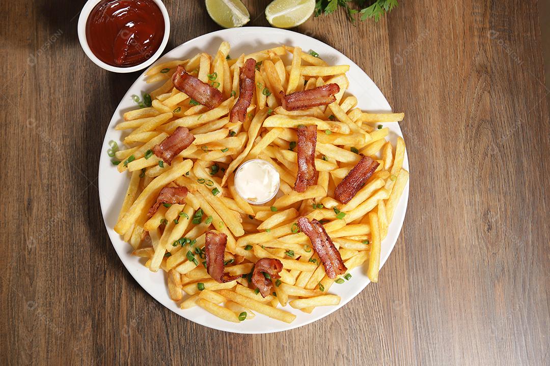 Portion of fries with bacon. Lettuce, chives, tomato, ketchup and mayonnaise.