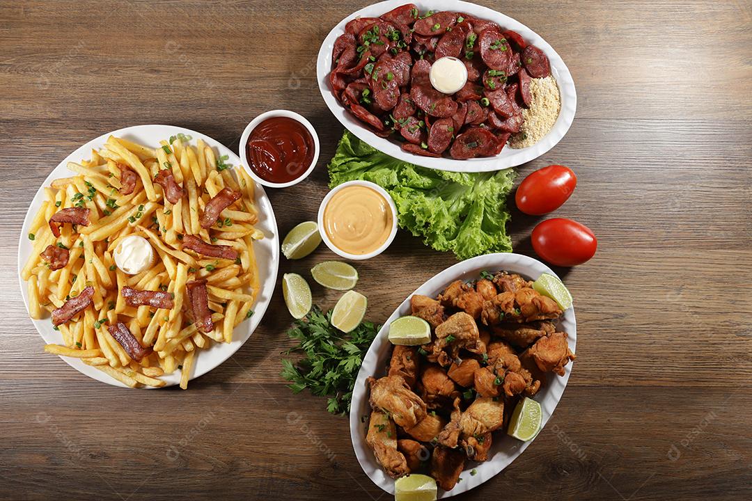 Porção de linguiça calabresa com limão, batata frita, bacon e frango frito. Alface, batata, cebolinha, ketchup e maionese.