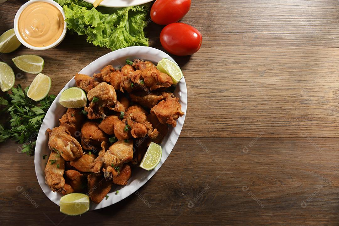 Porção de frango frito com limão. Alface, cebolinha, ketchup e maionese.