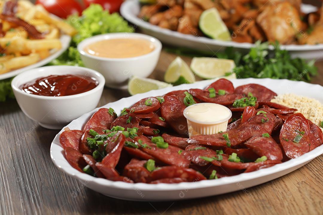 Porção de linguiça calabresa com limão. Alface, cebolinha, ketchup e maionese.