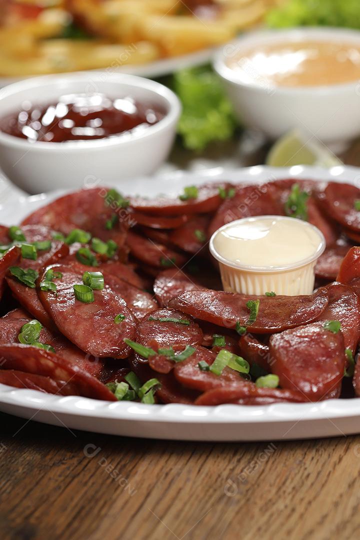 Porção de linguiça calabresa com limão. Alface, cebolinha, ketchup e maionese.