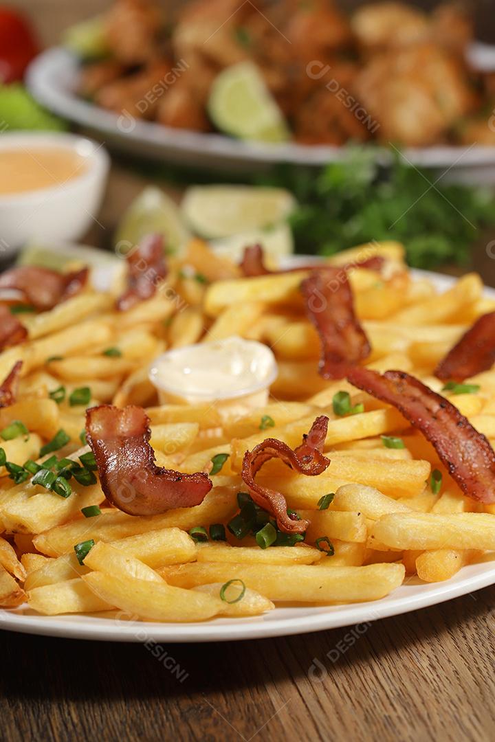 Portion of fries with bacon. Lettuce, chives, tomato, ketchup and mayonnaise.