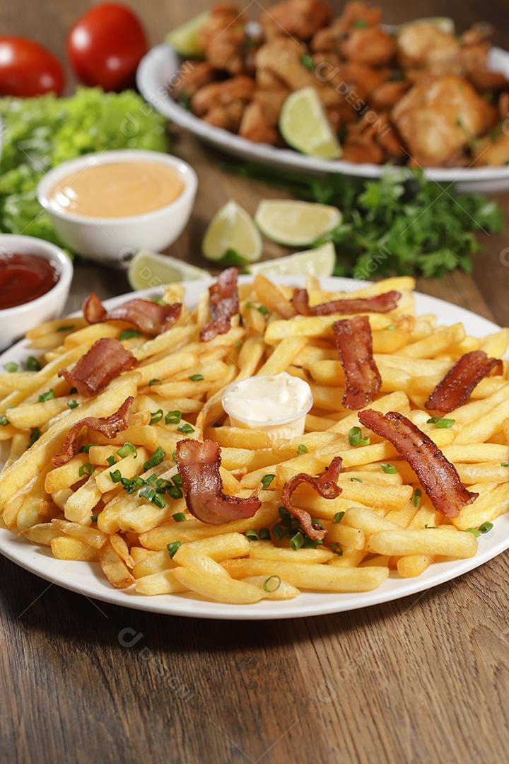 Porção de batata frita com bacon. Alface, cebolinha, tomate, ketchup e maionese.
