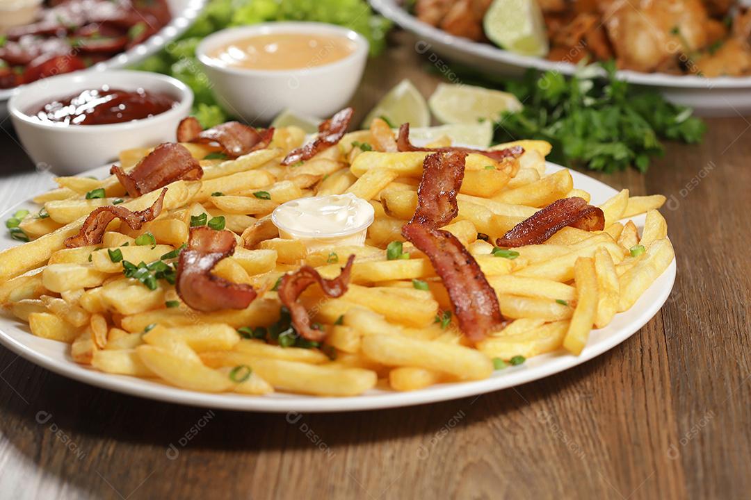 Porção de batata frita com bacon. Alface, cebolinha, tomate, ketchup e maionese.