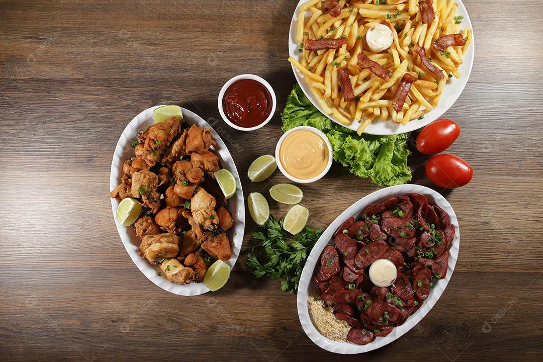 Porção de linguiça calabresa com limão, batata frita, bacon e frango frito. Alface, batata, cebolinha, ketchup e maionese.