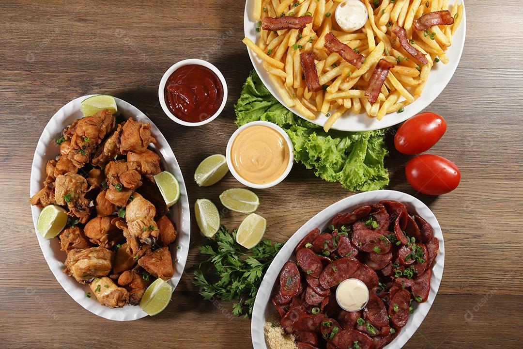 Porção de linguiça calabresa com limão, batata frita, bacon e frango frito. Alface, batata, cebolinha, ketchup e maionese.