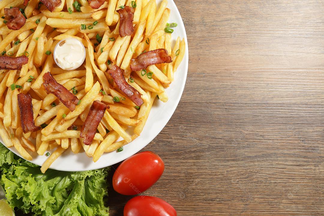 Porção de batata frita com bacon. Alface, cebolinha, tomate, ketchup e maionese.