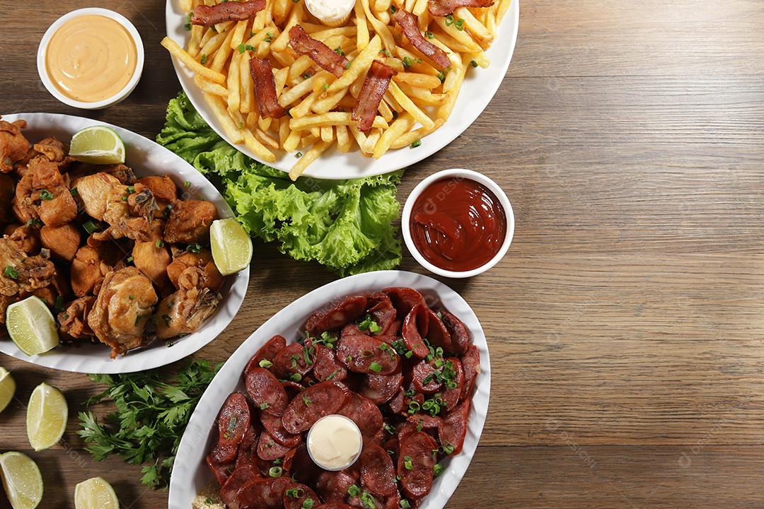 Porção de linguiça calabresa com limão, batata frita, bacon e frango frito. Alface, cebolinha, ketchup e maionese.