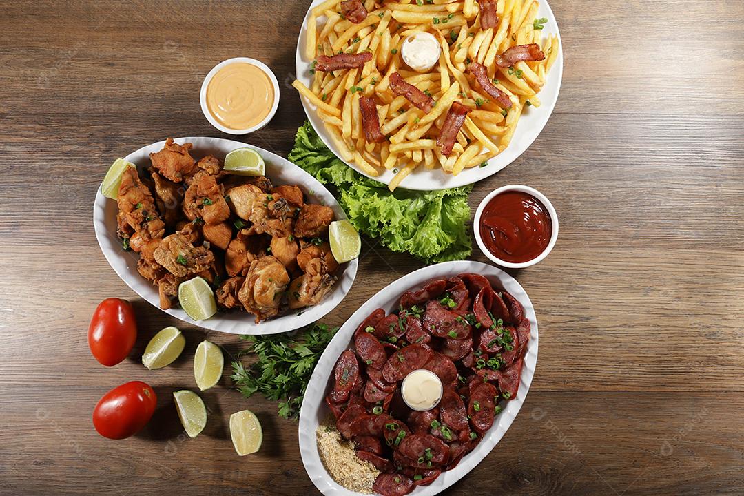 Porção de linguiça calabresa com limão, batata frita, bacon e frango frito. Alface, cebolinha, ketchup e maionese.