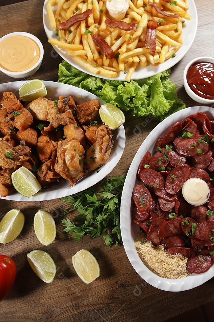 Porção de linguiça calabresa com limão, batata frita, bacon e frango frito. Alface, batata, cebolinha, ketchup e maionese.