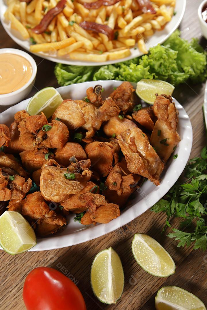 Porção de frango frito com limão. Alface, cebolinha, ketchup e maionese.