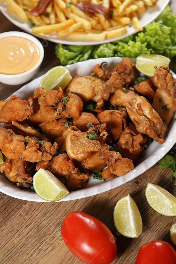 Porção de frango frito com limão. Alface, cebolinha, ketchup e maionese.