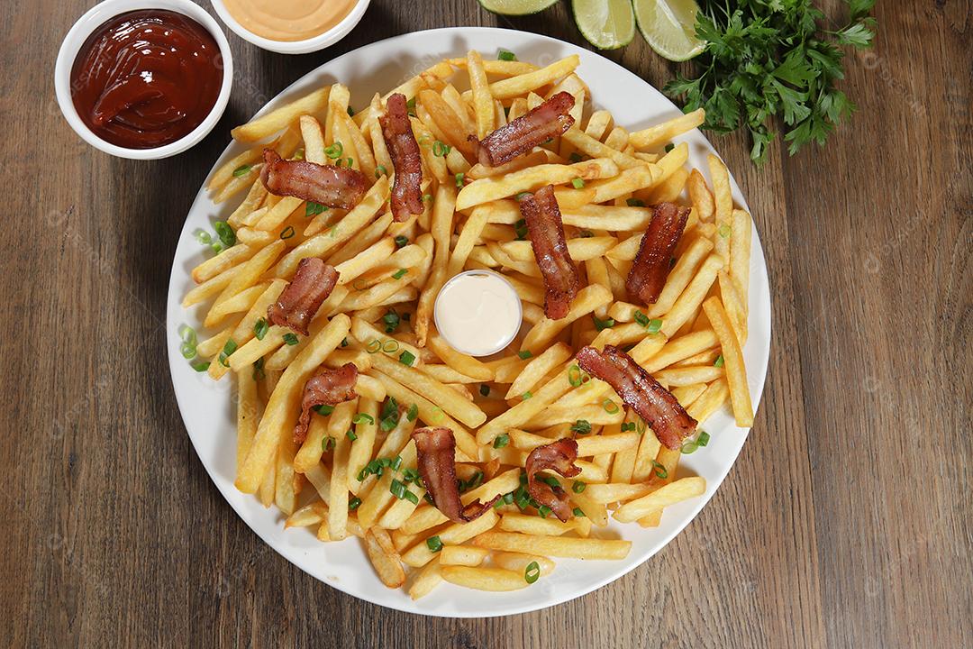 Porção de batata frita com bacon. Alface, batata, cebolinha, tomate, ketchup e maionese.