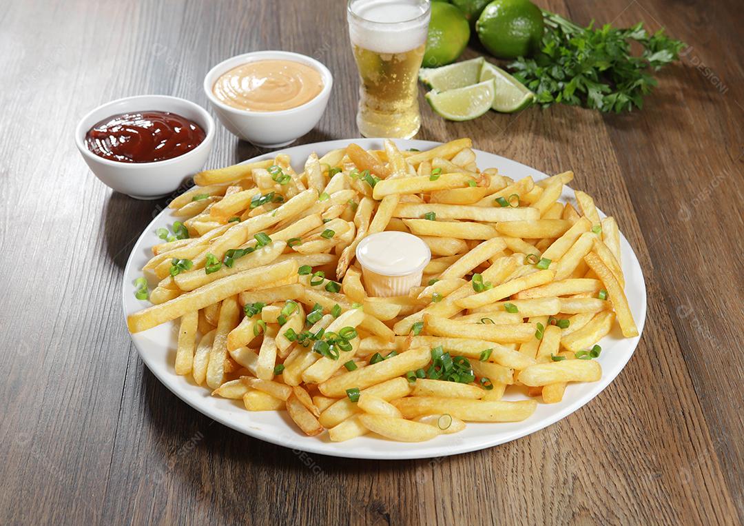 Porção de batatas fritas. Alface, batata, cebolinha, tomate, ketchup e maionese.