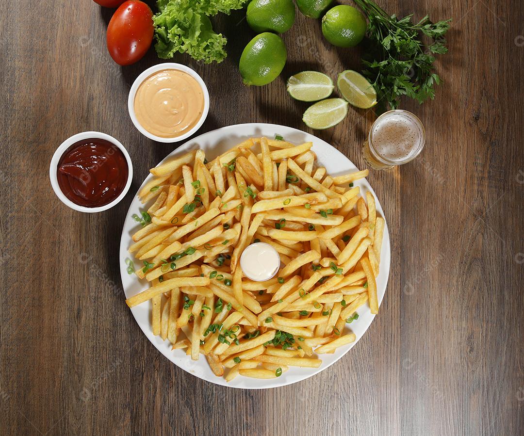 Porção de batatas fritas. Alface, batata, cebolinha, tomate, ketchup e maionese.