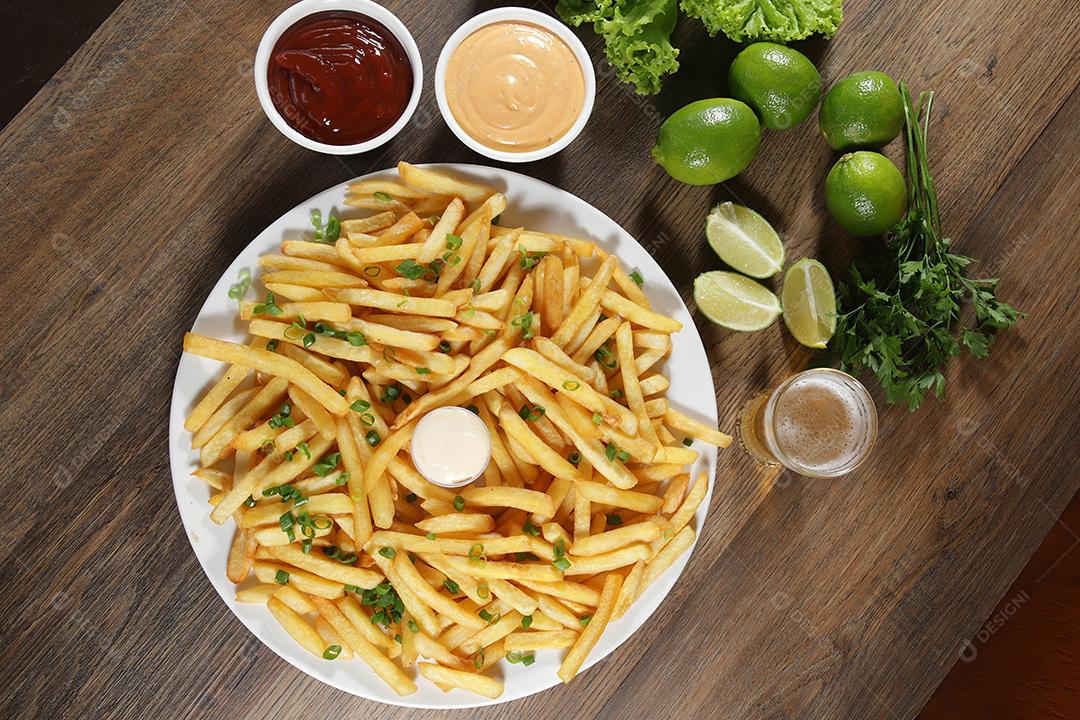 Porção de batatas fritas. Alface, batata, cebolinha, tomate, ketchup e maionese.
