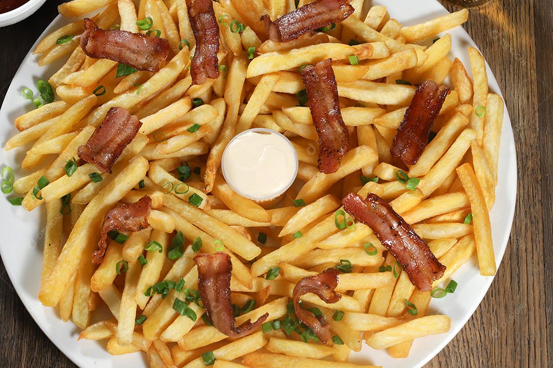 Porção de batata frita com bacon. Alface, batata, cebolinha, tomate, ketchup e maionese.