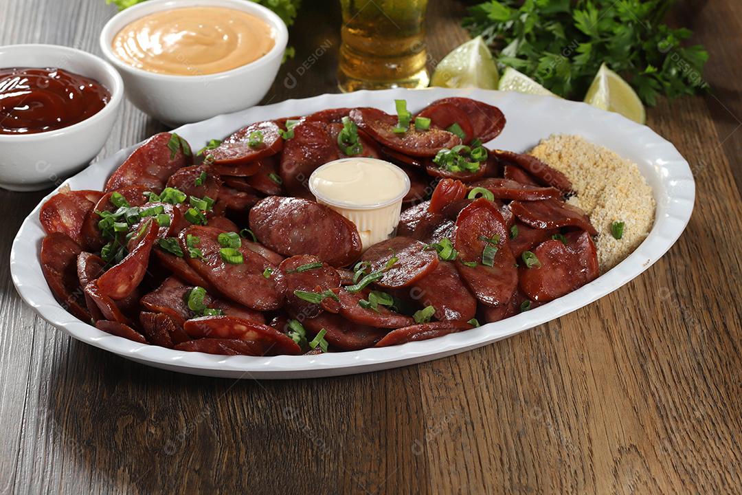 Porção de linguiça calabresa com limão. Alface, cebolinha, ketchup e maionese.