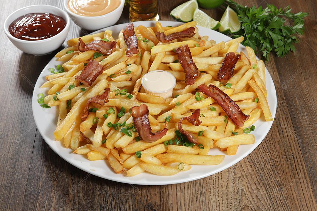 Porção de batata frita com bacon. Alface, batata, cebolinha, tomate, ketchup e maionese.