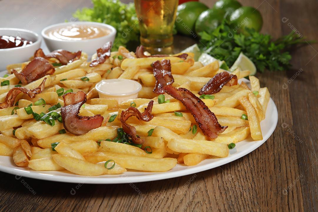 Porção de batata frita com bacon. Alface, batata, cebolinha, tomate, ketchup e maionese.