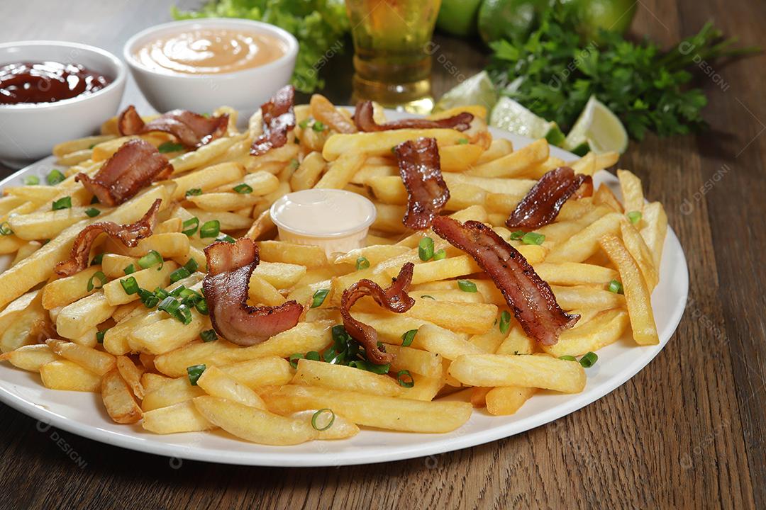 Porção de batata frita com bacon. Alface, batata, cebolinha, tomate, ketchup e maionese.