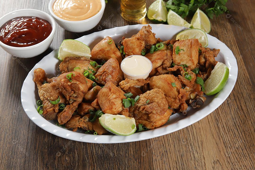 Portion of fried chicken with lemon. Lettuce, chives, ketchup and mayonnaise.